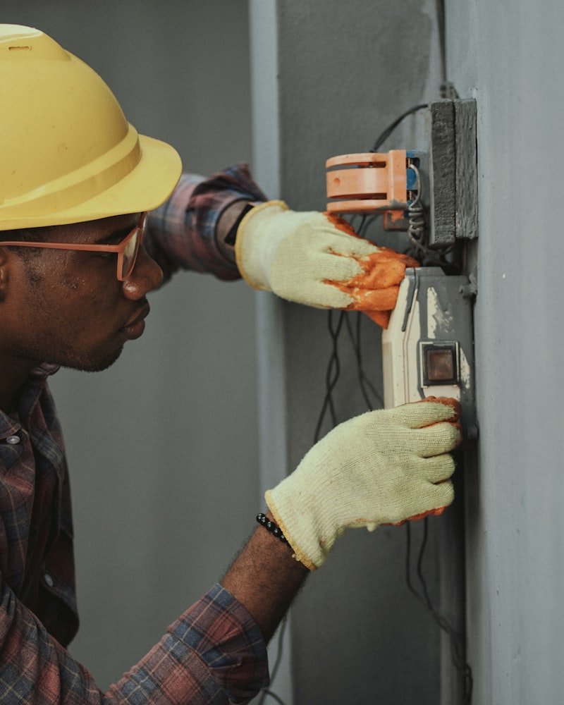 Professional Ottawa handyman working on an electrical fixture wearing a hard hat and safety glasses